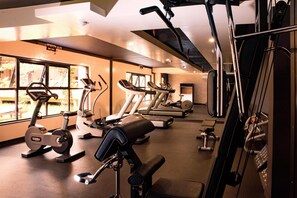 Un gimnasio con cintas de correr, elípticas y equipo de pesas.