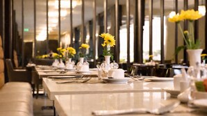 A restaurant with long tables set for dining, featuring yellow flowers and white tableware. - DoubleTree by Hilton Nairobi Hurlingham (Nairobi)