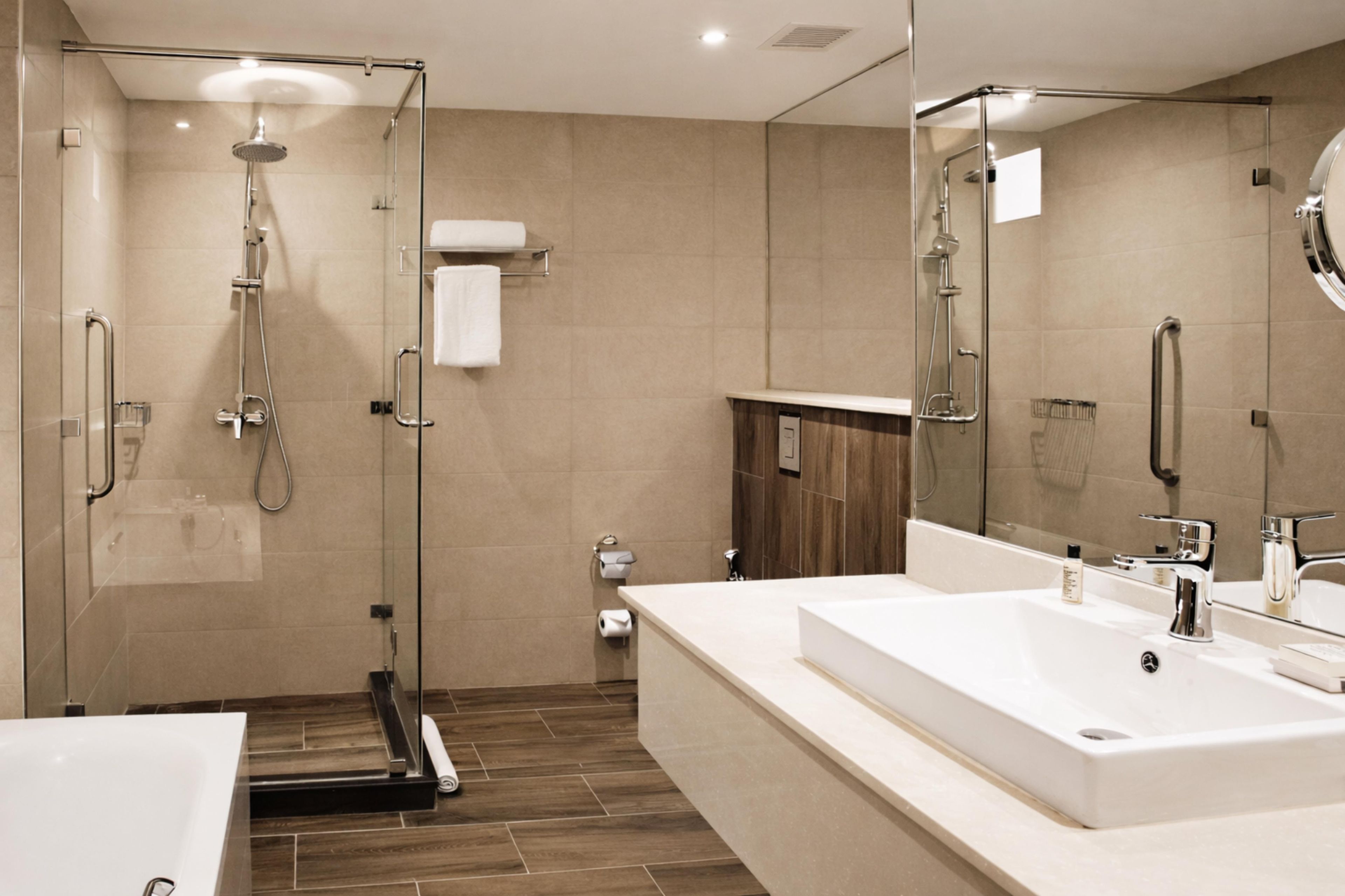 A modern bathroom with a glass-enclosed shower, a large white sink, and a mirror.