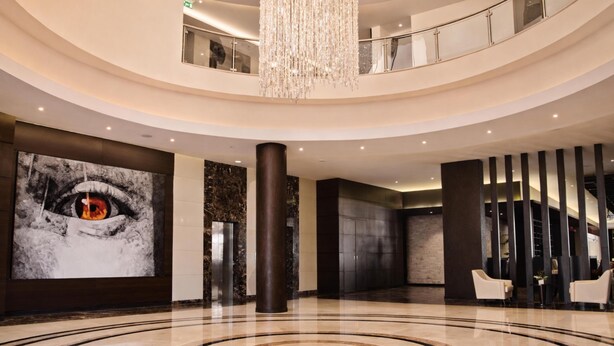 A spacious lobby with a large chandelier, a prominent eye artwork, a marble floor, and a modern elevator. - DoubleTree by Hilton Nairobi Hurlingham (Nairobi)