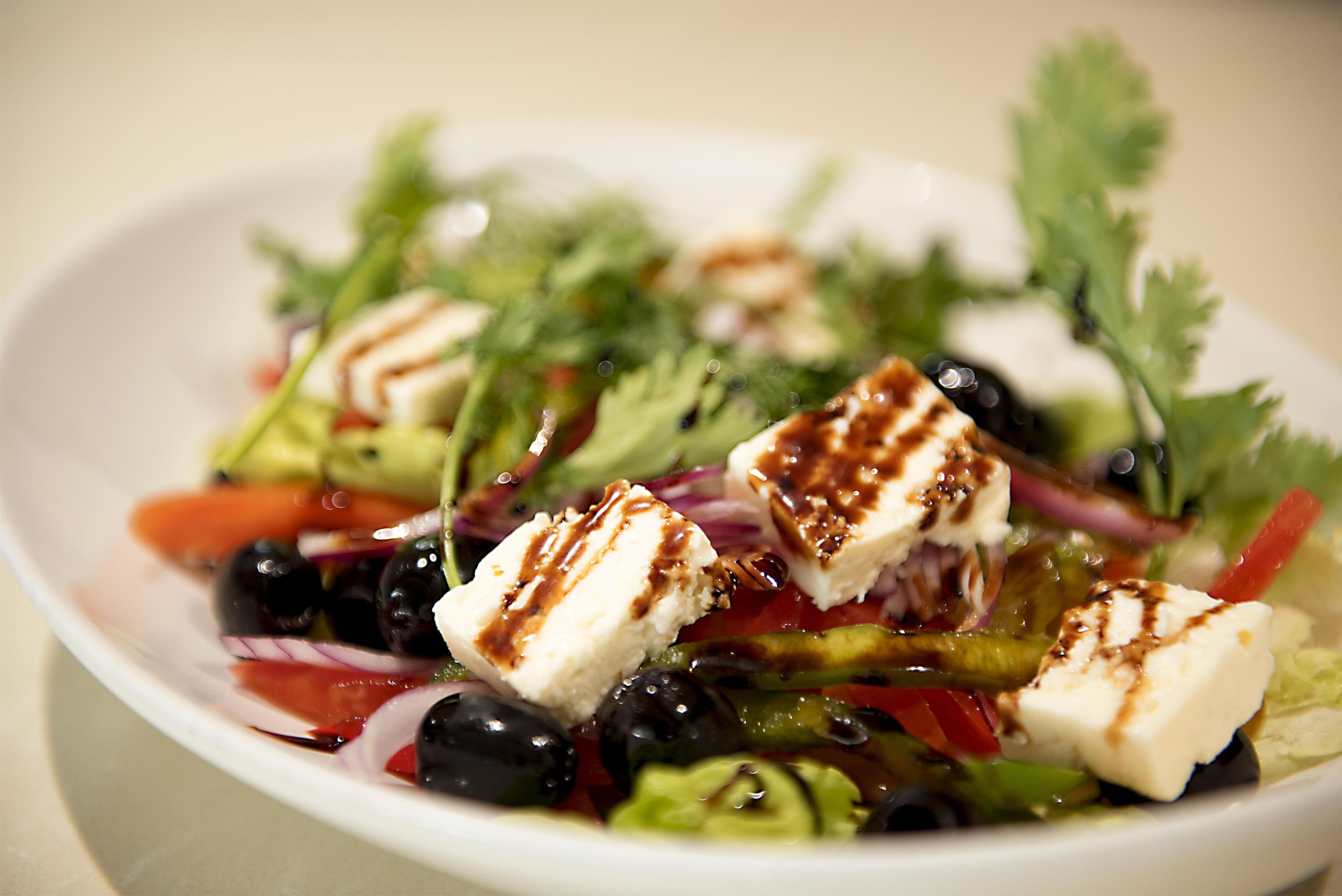 A bowl of salad with feta cheese, olives, and vegetables.