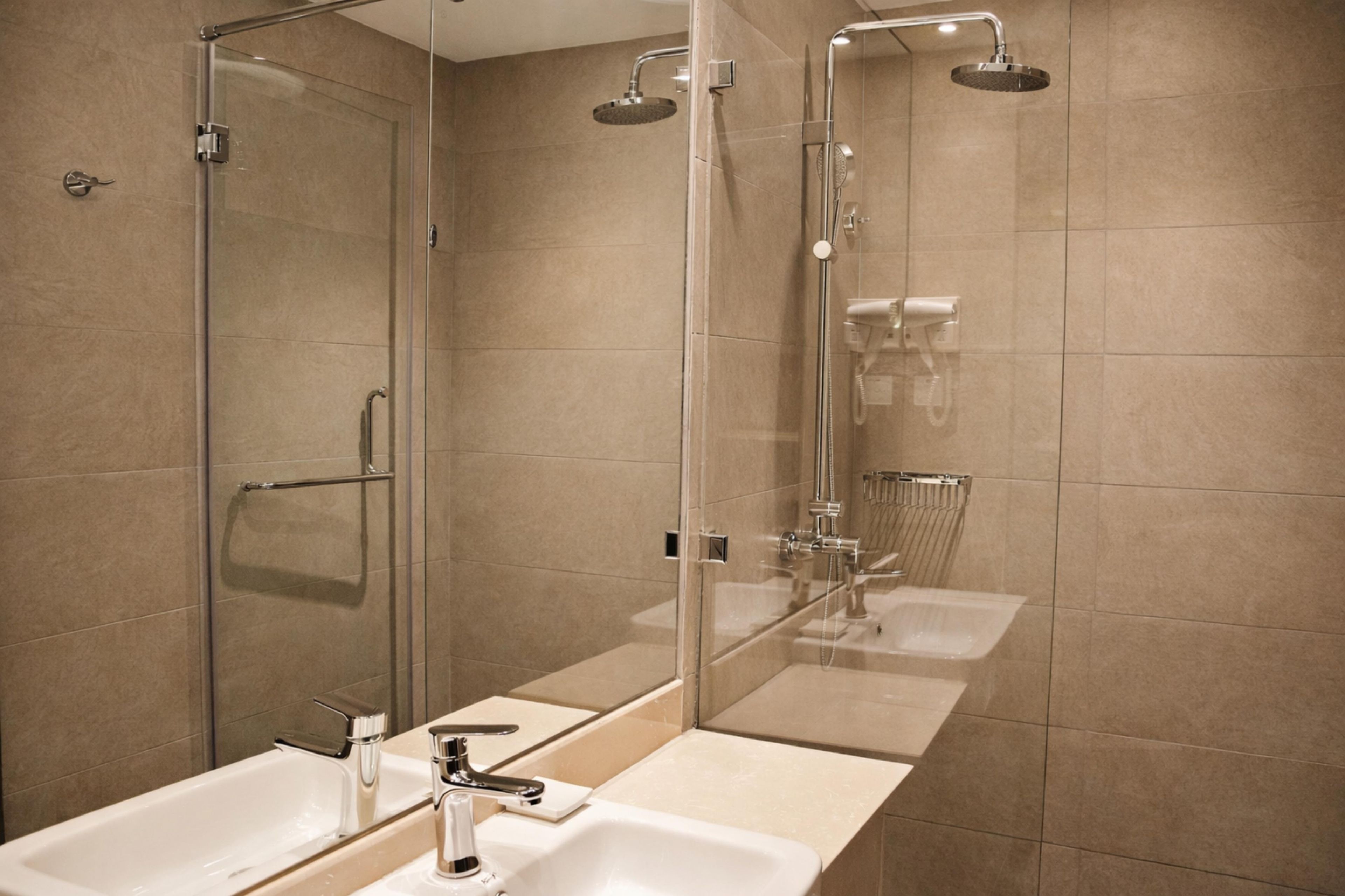 A modern bathroom with a glass shower enclosure, a large mirror, and two sinks.