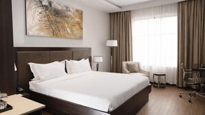 A hotel room with a large bed, a desk, a chair, a lamp, and a painting on the wall. - DoubleTree by Hilton Nairobi Hurlingham (Nairobi)