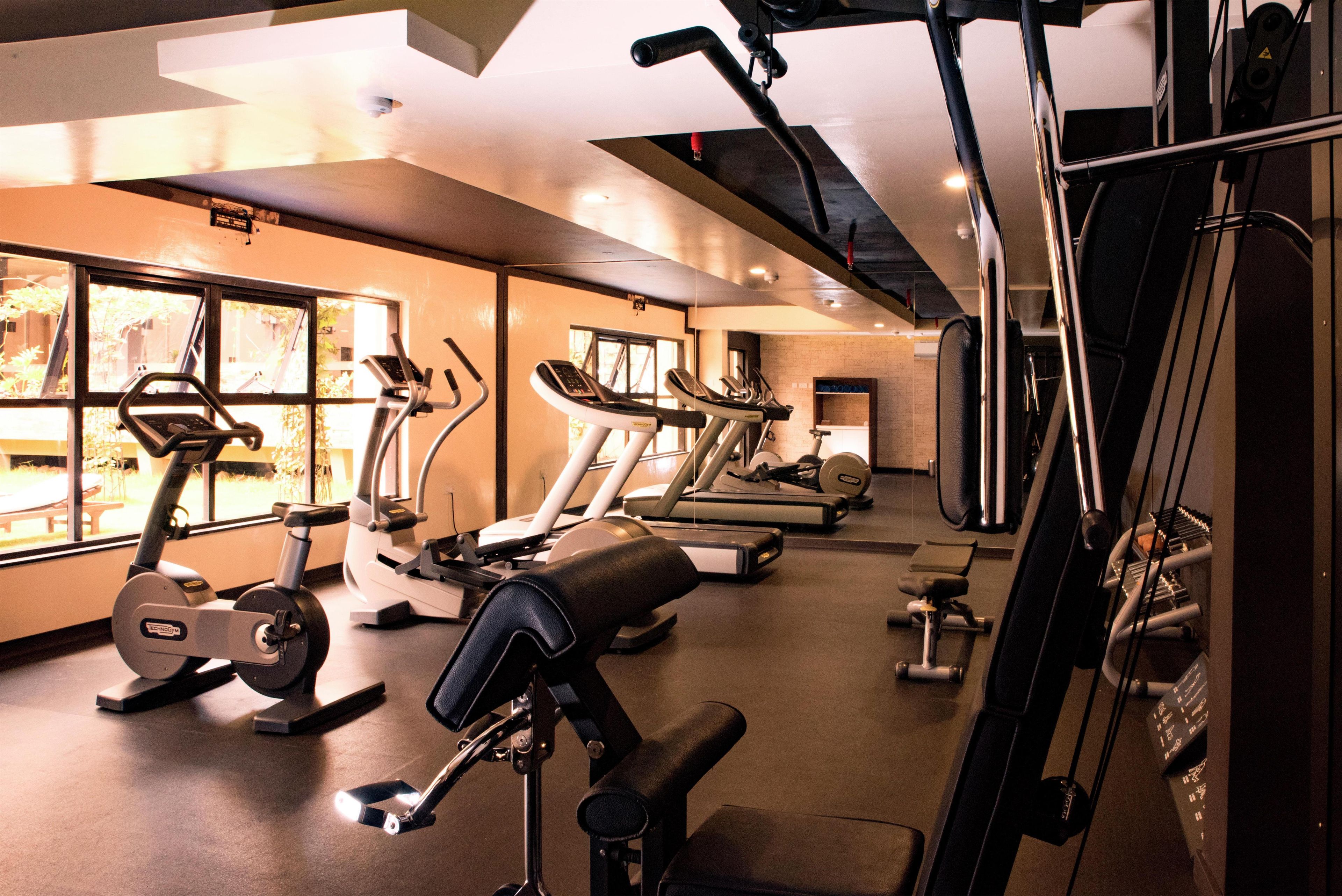 Une salle de sport équipée de tapis de course, de vélos elliptiques et de matériel de musculation.