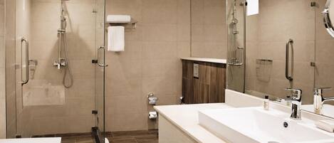Une salle de bain moderne avec une douche à parois de verre, un grand lavabo blanc et un miroir.
