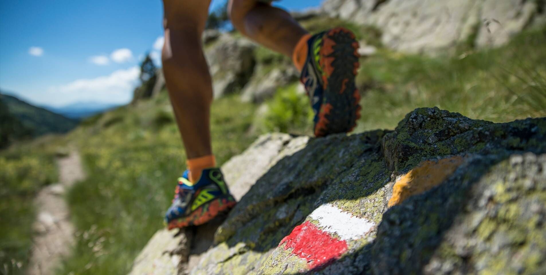 A person hiking on a rocky path with colorful shoes.