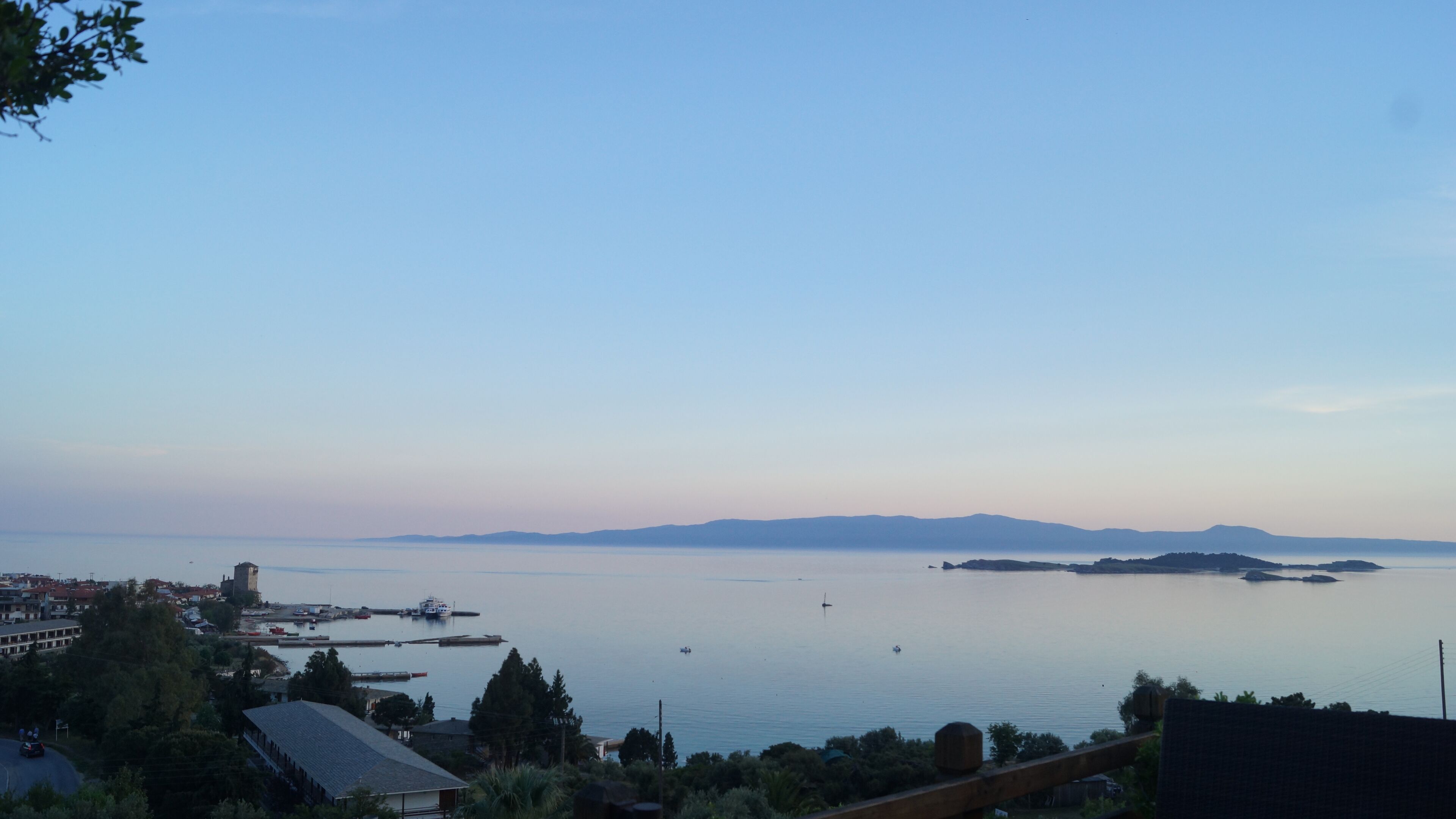 A coastal view with a marina, boats, and distant mountains.