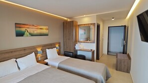 Een moderne hotelkamer met twee bedden, een houten hoofdbord, een schilderij van een ondergaande zon, een bureau met spiegel en een inloopkast.