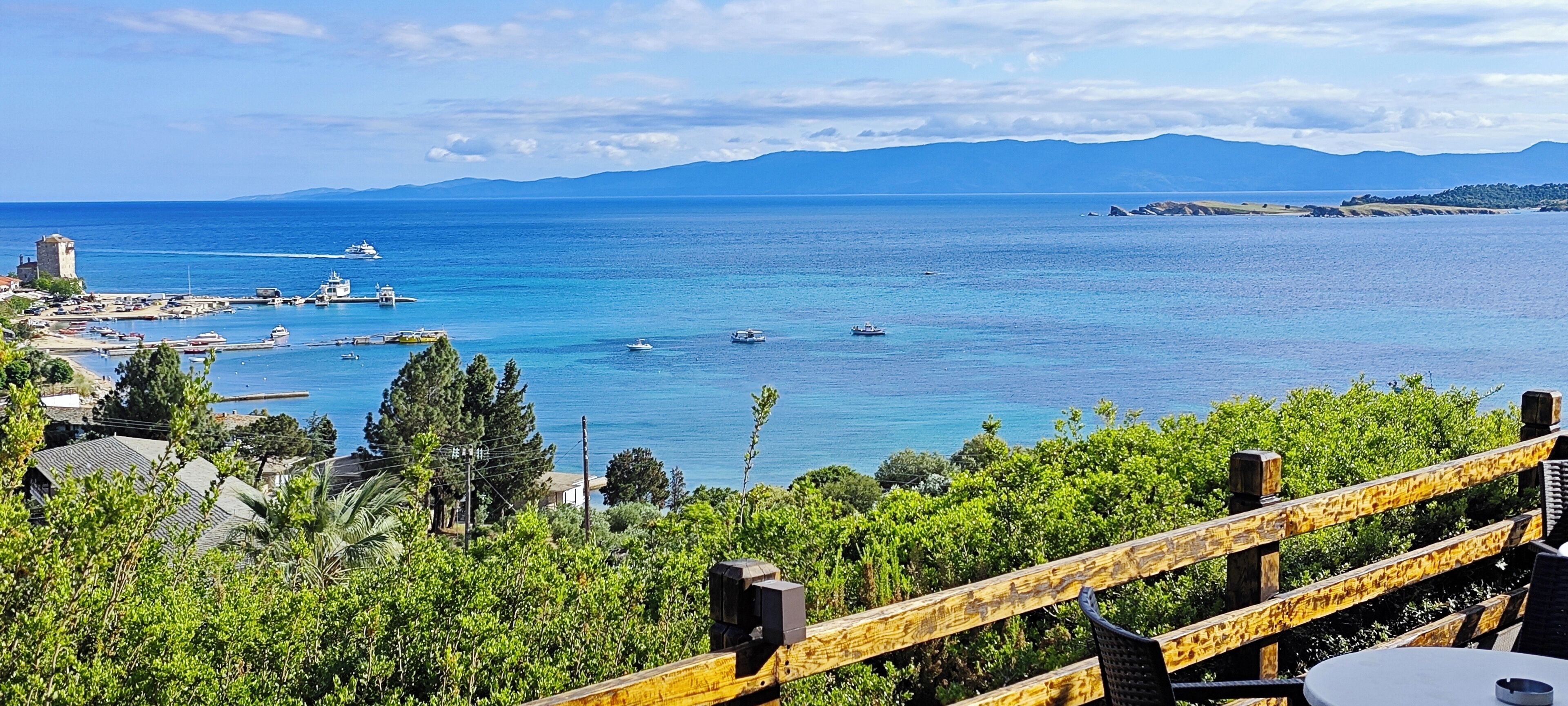 A coastal view with a marina, boats, and a distant mountain range.