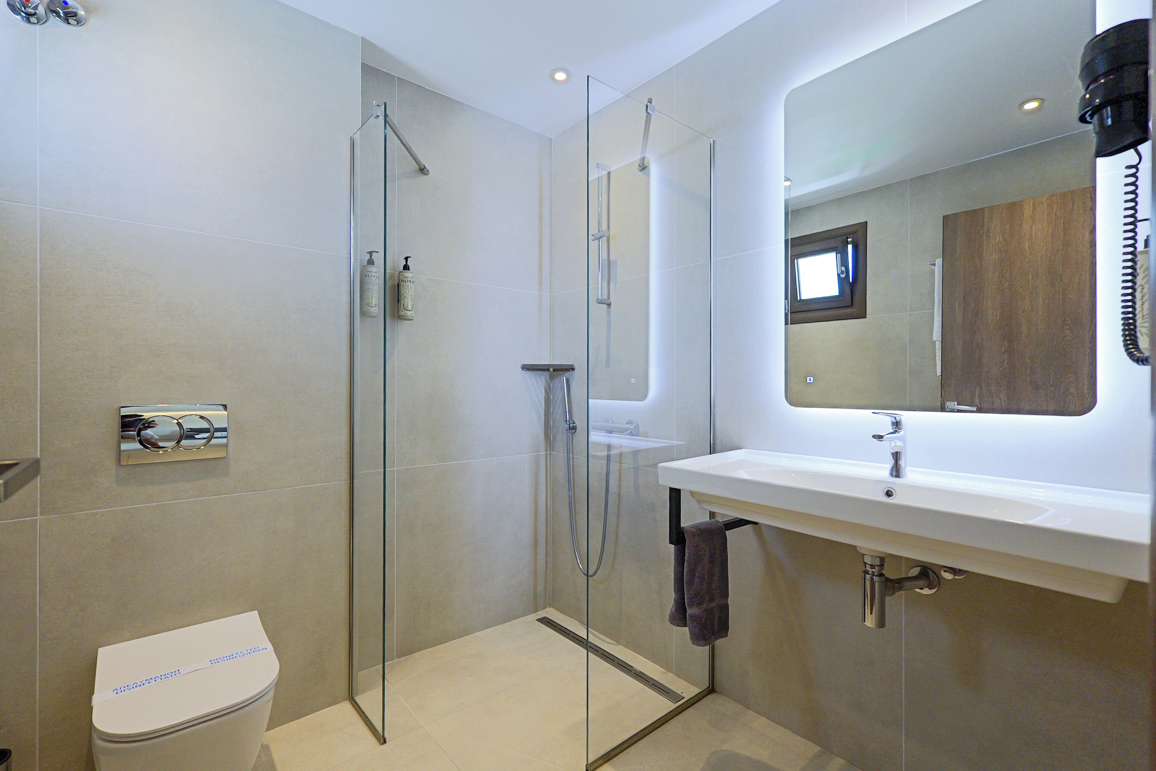 A modern bathroom with a glass-enclosed shower, a white sink, and a mirror above it.