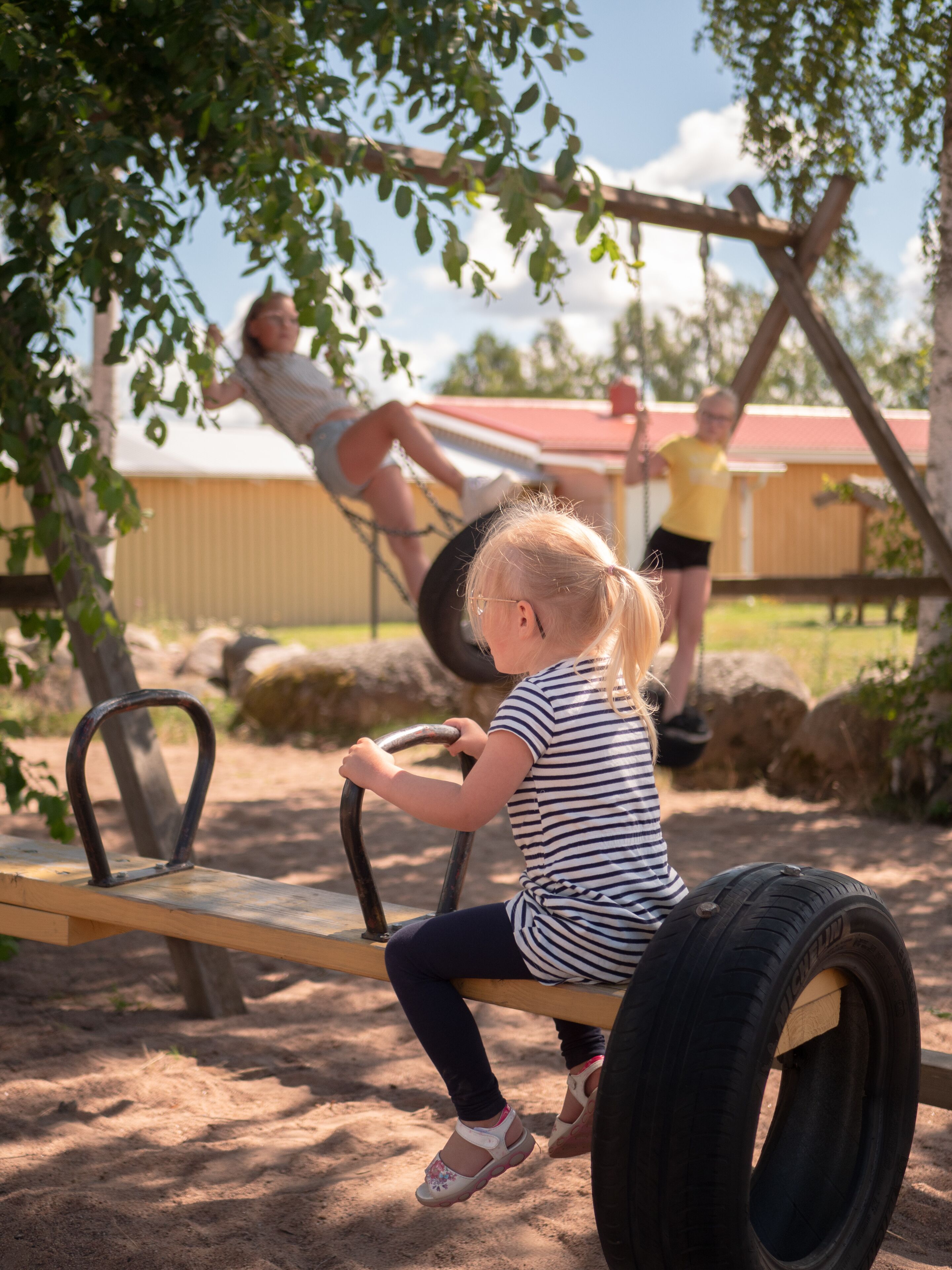Un enfant qui joue sur une balançoire faite d’un pneu dans un parc.