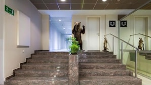 A hotel lobby with marble stairs, a reception desk, and a bear statue. - Hotel Macola (Plitvicka Jezera)