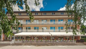 A hotel with a covered outdoor seating area, multiple balconies, and a clear blue sky. - Hotel Macola (Plitvicka Jezera)