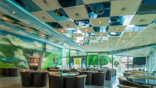 A spacious lobby with a modern ceiling design, multiple seating areas, and a large screen displaying a nature scene. - Hotel Macola (Plitvicka Jezera)