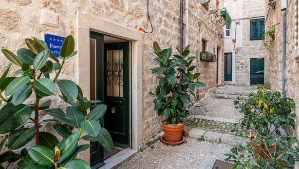 A narrow stone alleyway with a door leading to a room, potted plants, and a blue sign on the wall. - Villa Mirabilis, stunning superior villa, Dubrovnik Old Town (Dubrovnik)