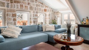 A cozy living room with a stone wall, a blue sofa, and a wooden coffee table. - Villa Mirabilis, stunning superior villa, Dubrovnik Old Town (Dubrovnik)