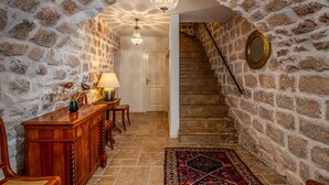 A stone-walled hallway with a wooden desk, chairs, a chandelier, and a staircase. - Villa Mirabilis, stunning superior villa, Dubrovnik Old Town (Dubrovnik)
