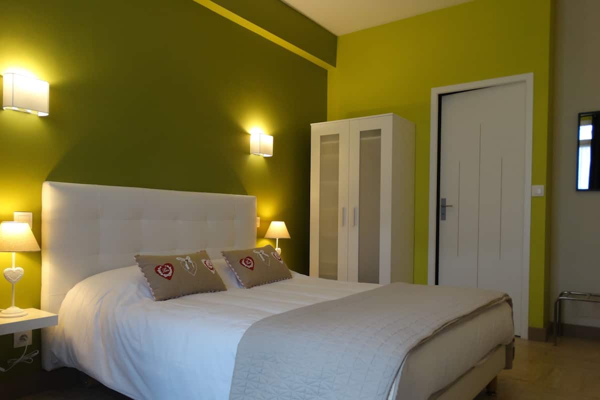 A bedroom with a bed, nightstands, a wardrobe, and a door.