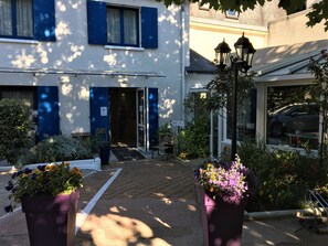 A building with a reception area, a paved entrance, and potted plants. - Hotel Le Castel Fleuri (Tours)