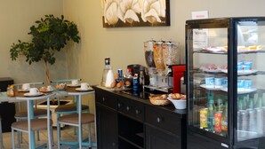 A breakfast area with a coffee machine, beverage dispensers, and a refrigerator stocked with beverages. - Hotel Le Castel Fleuri (Tours)