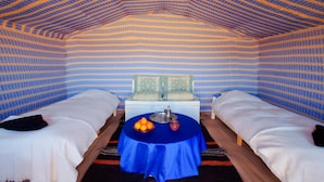 A room with two beds, a table with oranges and a teapot, and patterned walls and ceiling. - La Dune Blanche (M'Hamid El Ghizlane)