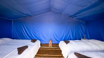 Una tenda con due letti, una zona centrale con tappeto e una lanterna.