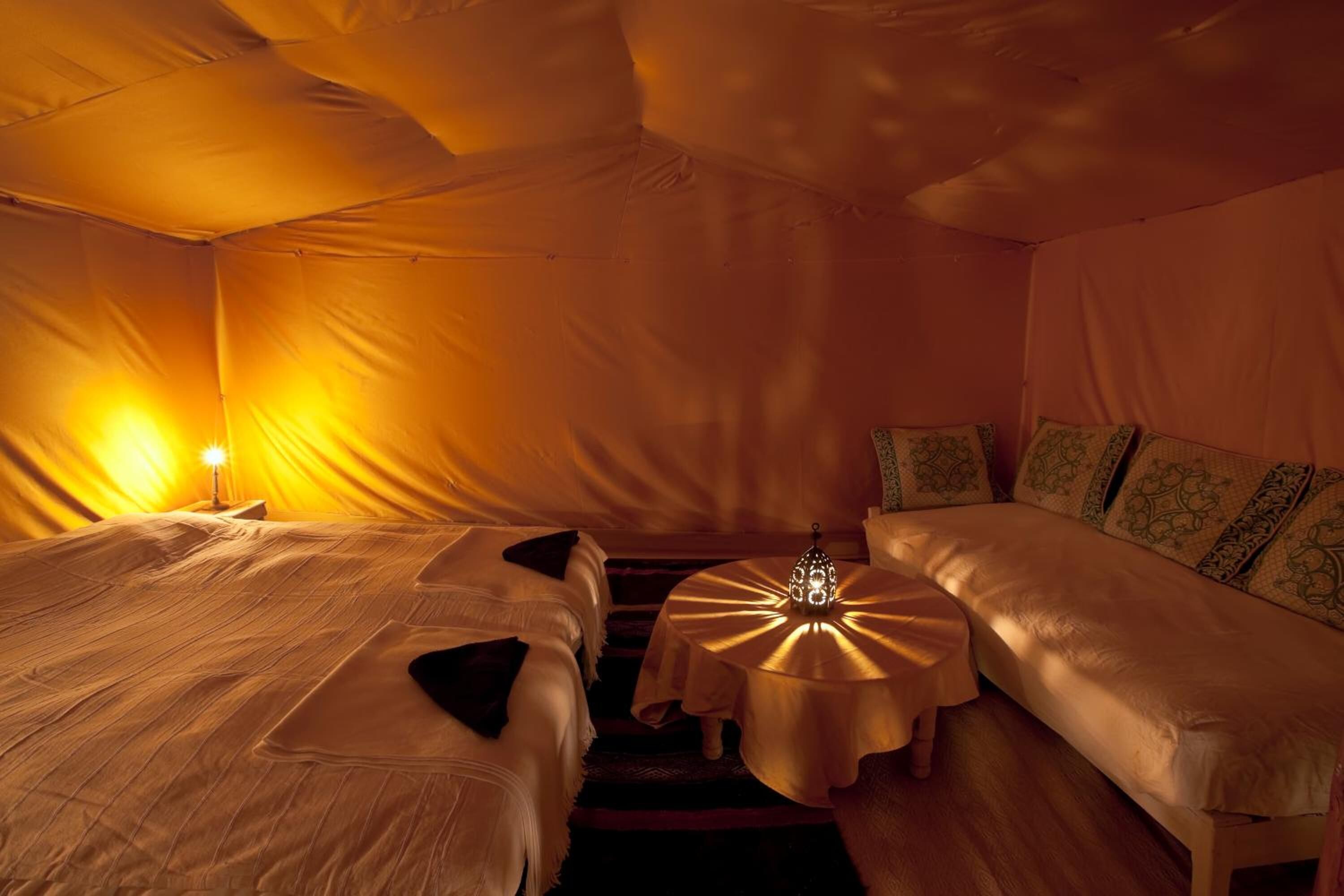A cozy room with a bed, a sofa, and a small table with a lamp.