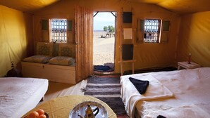 A tented room with two beds, a small table with a tray, and a view of the desert. - La Dune Blanche (M'Hamid El Ghizlane)