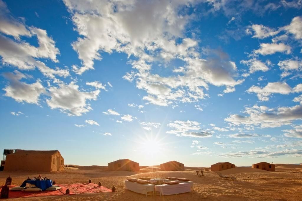 Paisaje desértico con varias tiendas de campaña y cielo despejado.