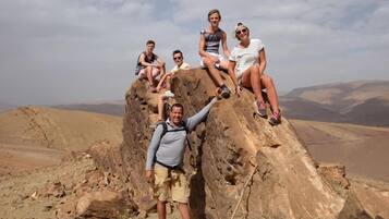 Un grupo de personas sentadas sobre un afloramiento rocoso, con un paisaje montañoso al fondo.