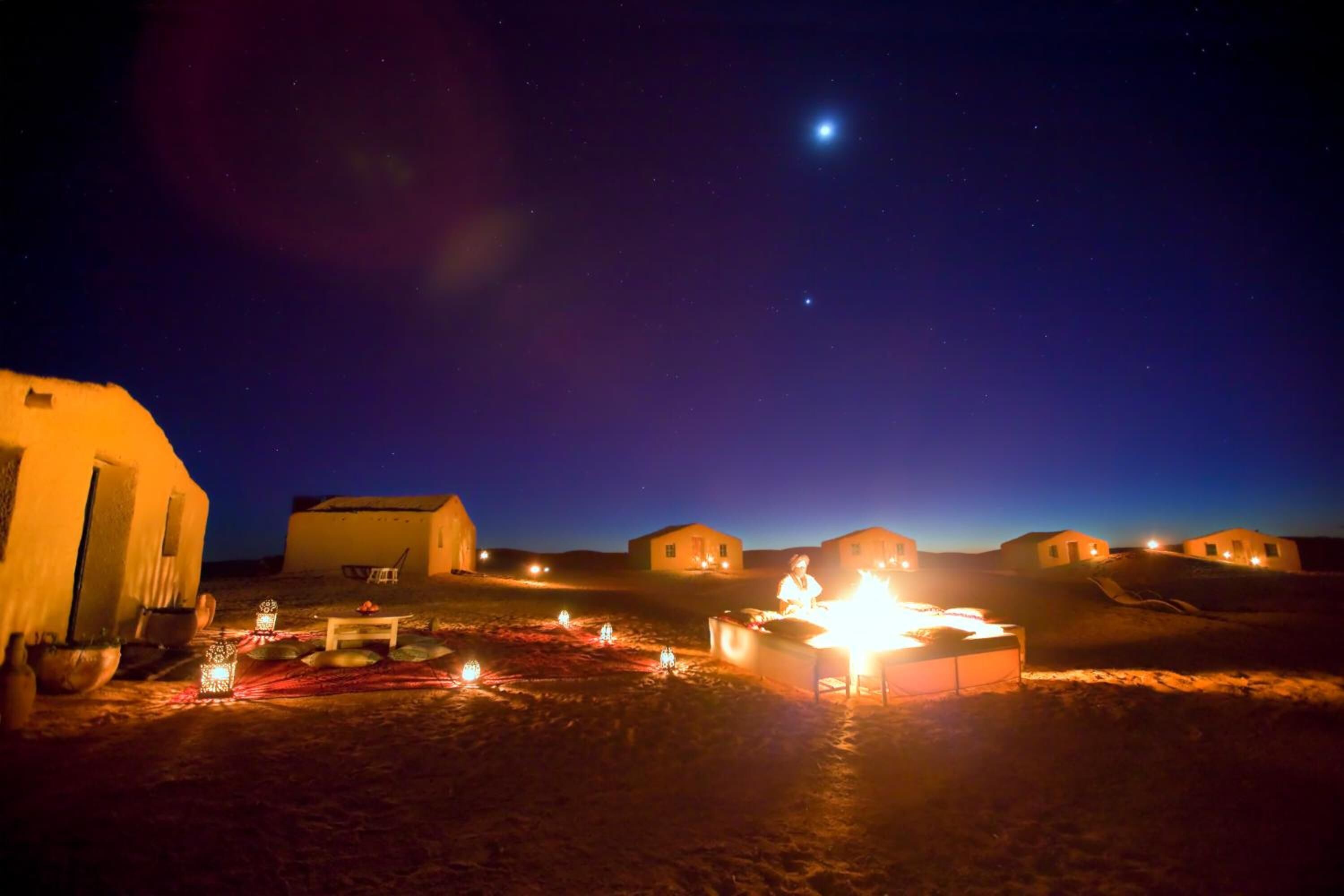 Un campamento en el desierto con varias tiendas de campaña y un hogar central.