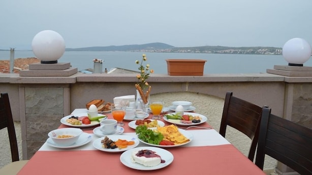 A table set with breakfast items overlooking a body of water. - Ayvalik Palas Hotel (Ayvalik)