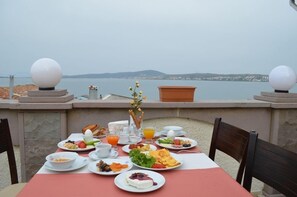 Mesa servida con alimentos para el desayuno con vista a un cuerpo de agua.