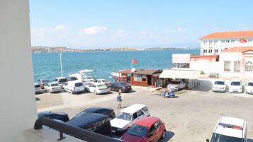 A coastal parking area with several cars and a small building with a red flag.
