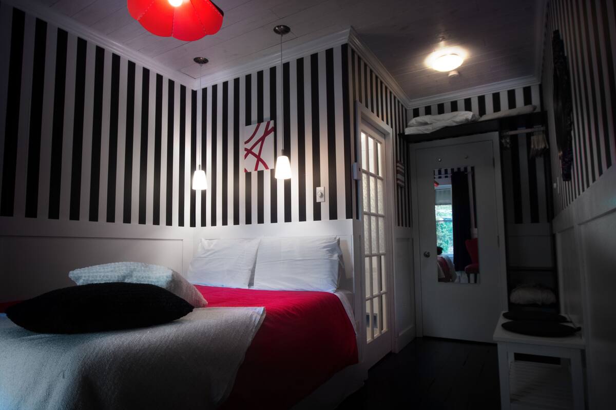 A room with a bed, striped walls, and a window.