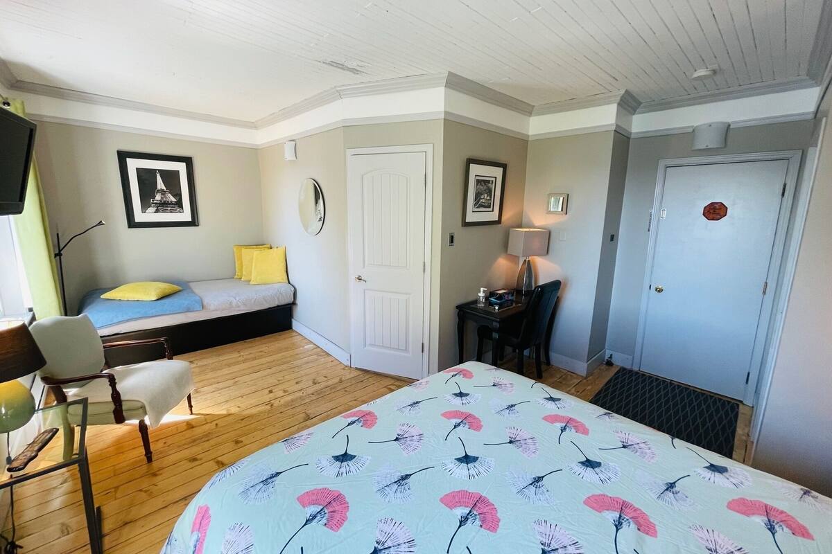 A compact bedroom with a bed, a desk, a chair, and a door.