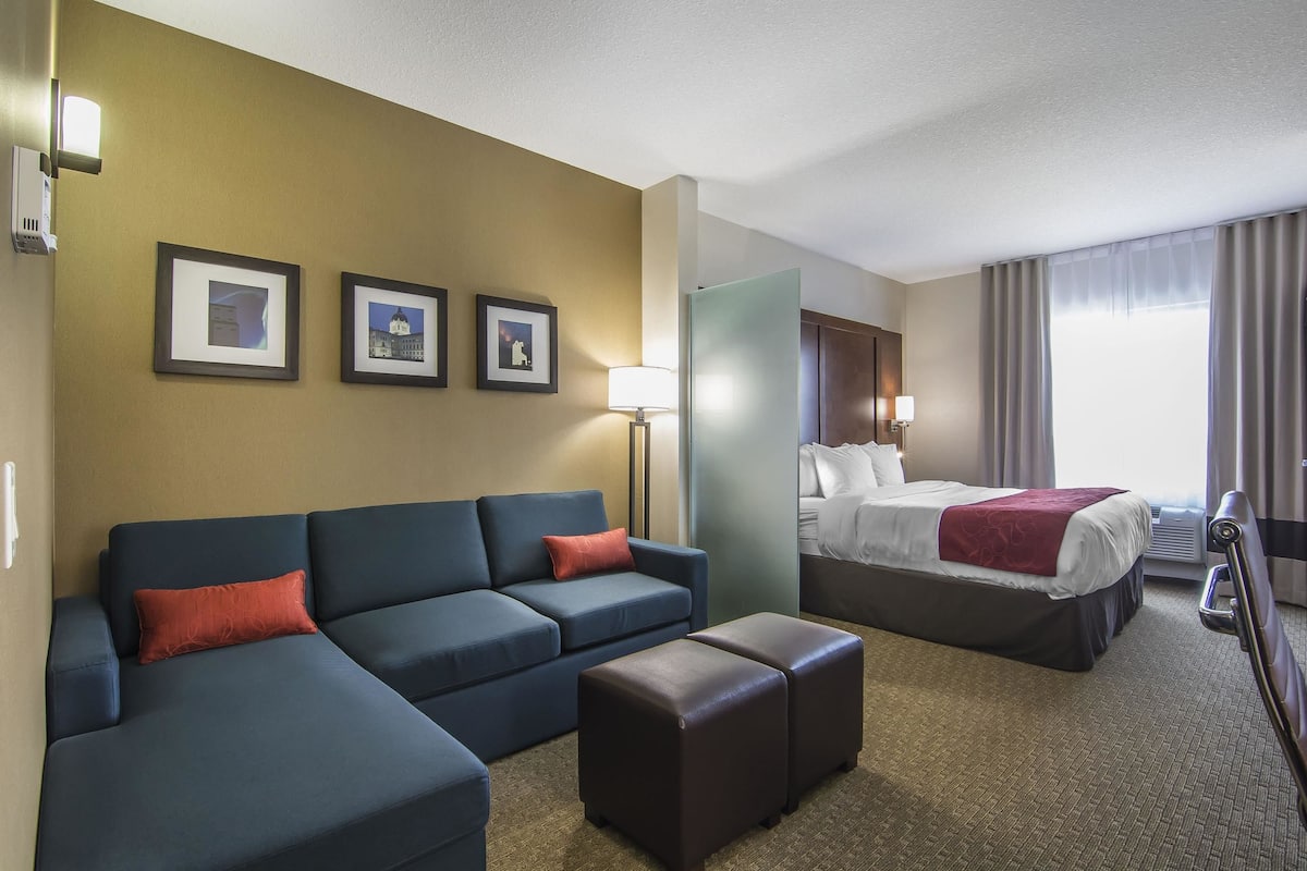 A hotel room with a sofa, a bed, a coffee table, and three framed pictures on the wall.