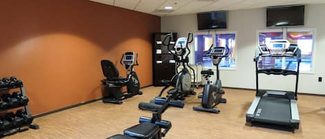 A gym with treadmills, elliptical machines, and free weights.