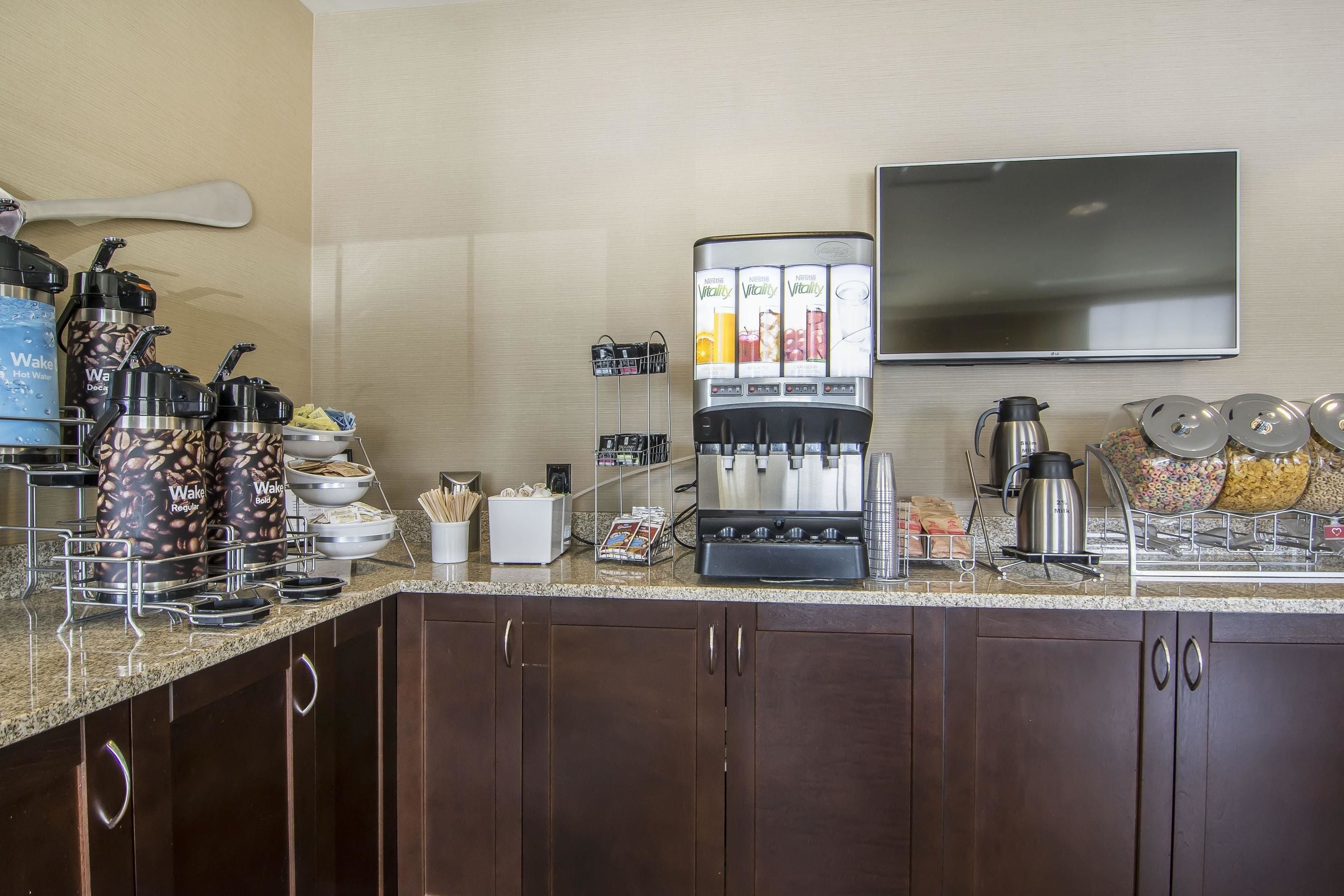 A hotel breakfast area with a coffee machine, cereal, and condiments.