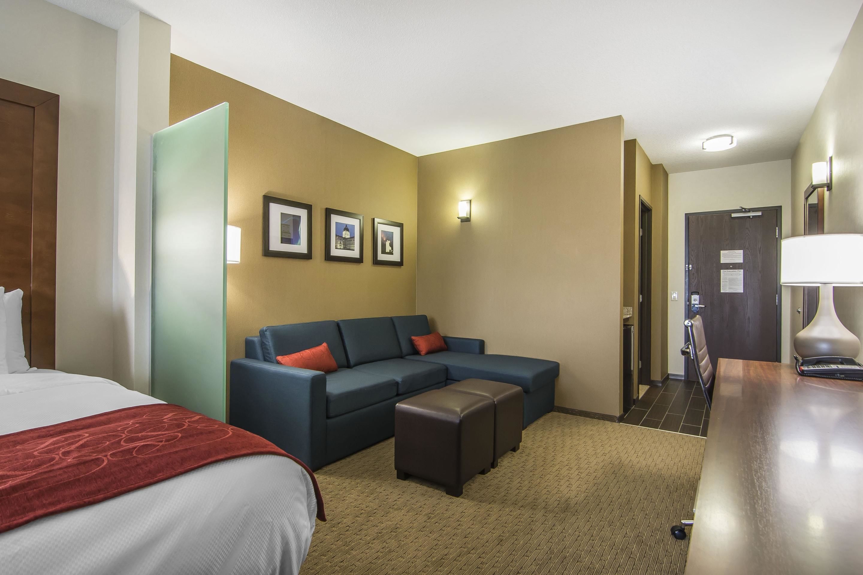A hotel room with a bed, a sofa, a coffee table, and a desk.