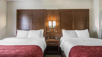 A double room with two beds, a wooden headboard, bedside tables with lamps, and a carpeted floor.