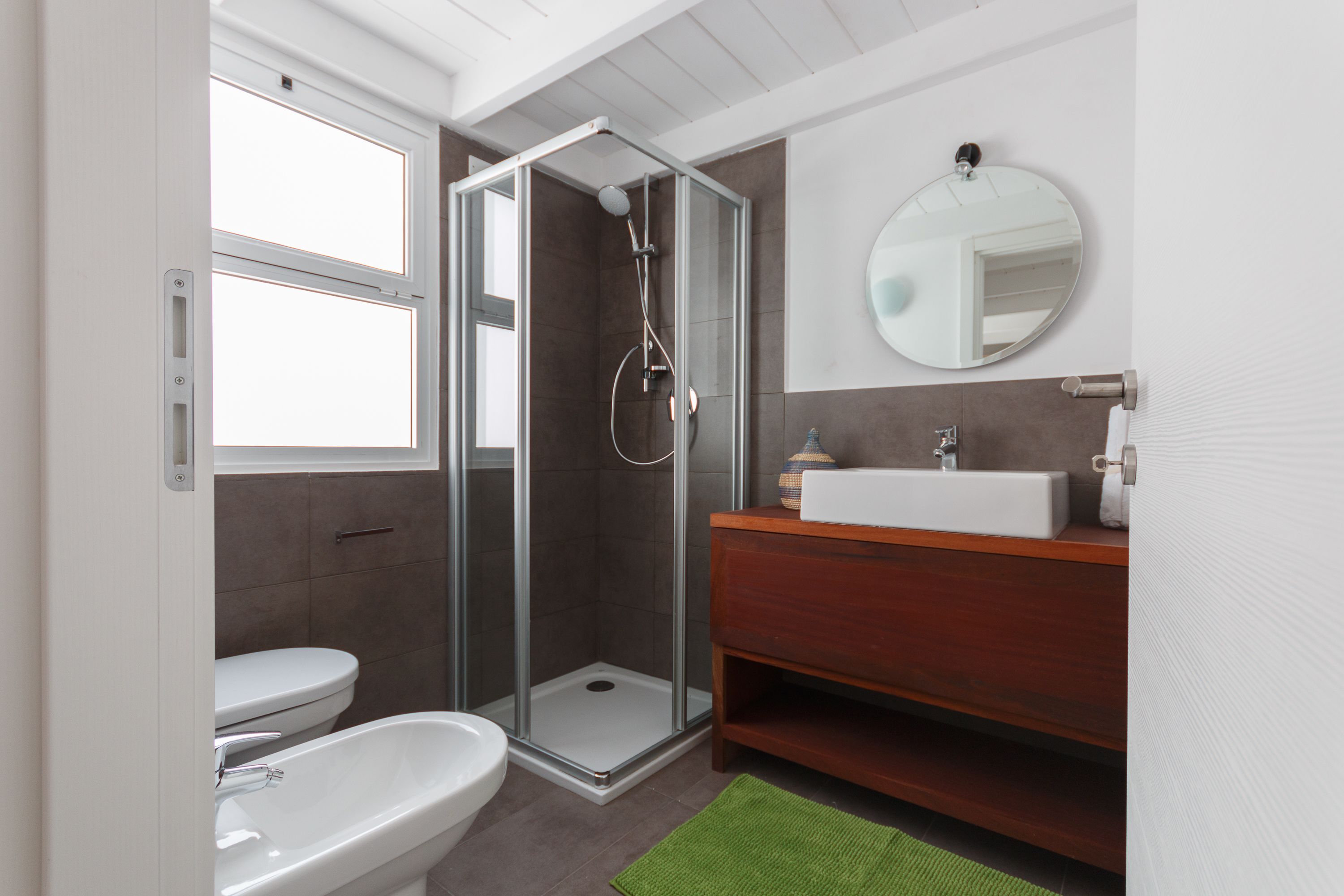 Ein modernes Badezimmer mit einer Duschkabine, einer weißen Toilette und einem hölzernen Waschtisch.