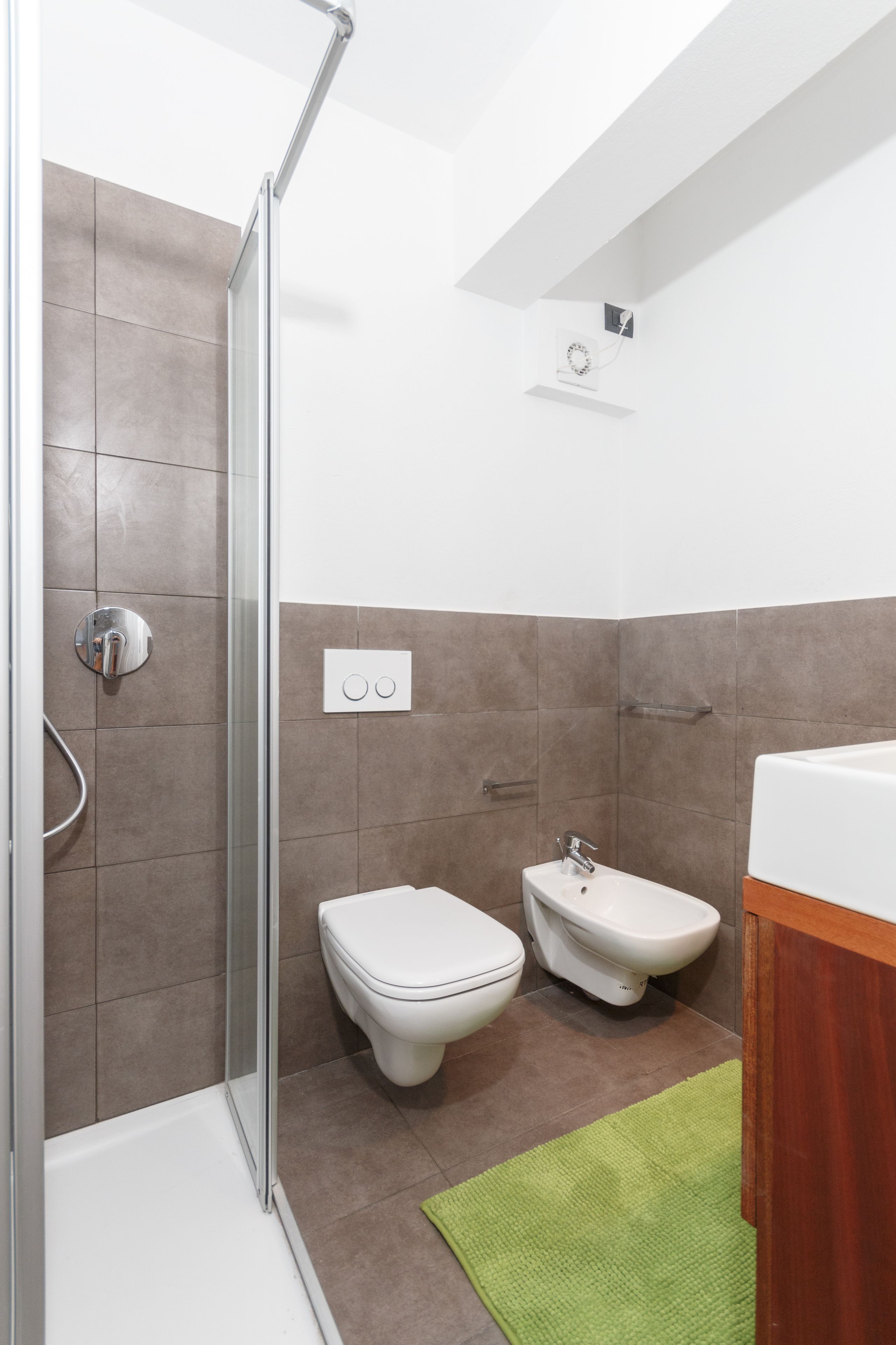 A modern bathroom with a glass shower enclosure, a toilet, and a bidet.