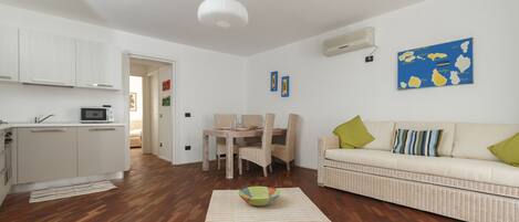 A modern living room with a sofa, a coffee table, and a dining area with chairs and a table.