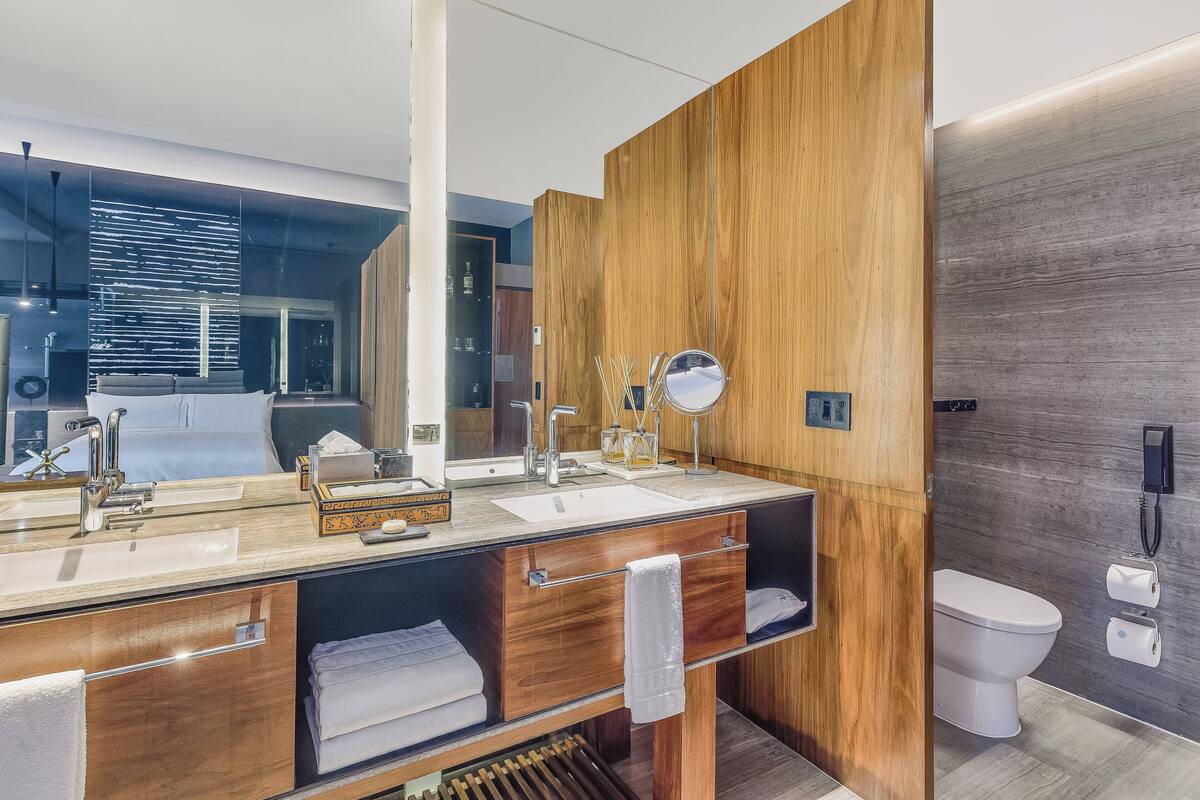 Un baño moderno con tocador de madera, un espejo grande y un inodoro.