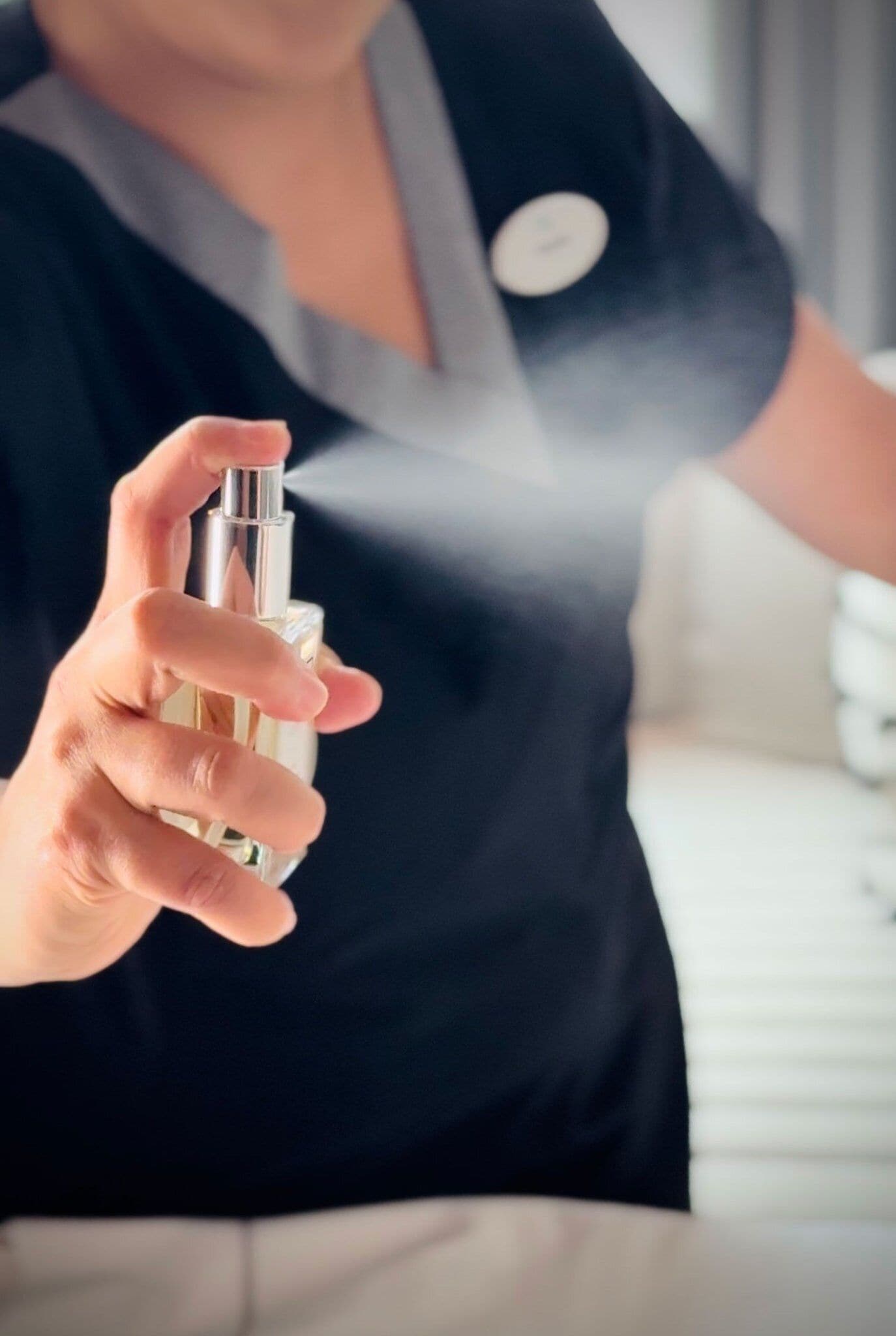 Une personne tenant un flacon pulvérisateur, probablement contenant un produit de nettoyage ou un produit d’hygiène personnelle.