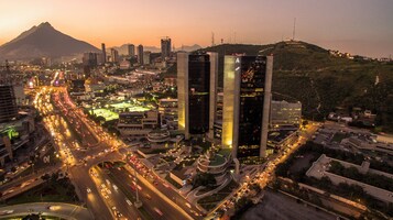 A cityscape with a prominent modern building, busy roads, and a mountain in the background.