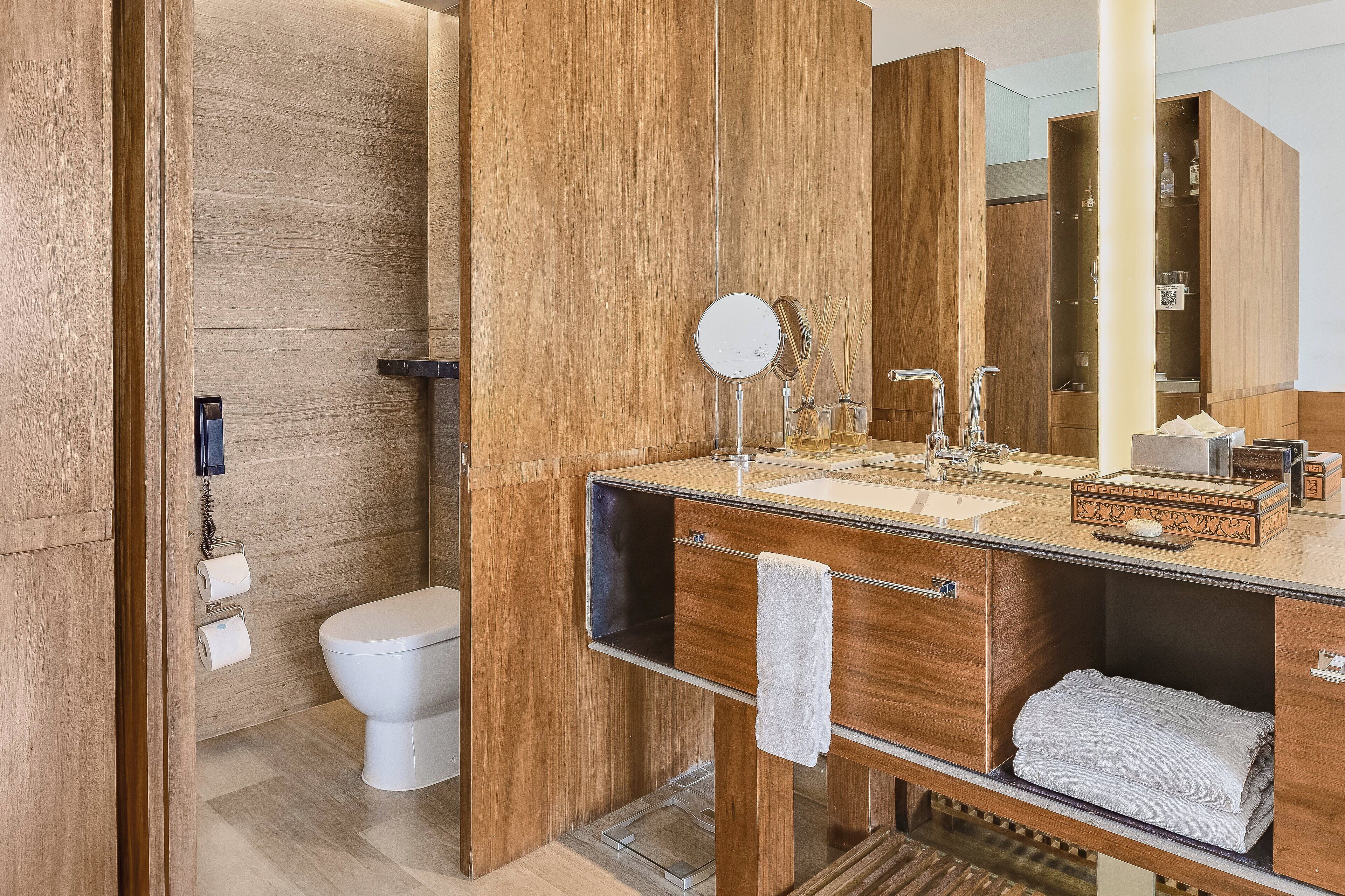 Un baño moderno con tocador de madera, inodoro y espejo grande.