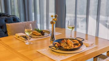 Une table à manger avec des plats de fruits de mer, des verres à vin et un vase rempli de fleurs.