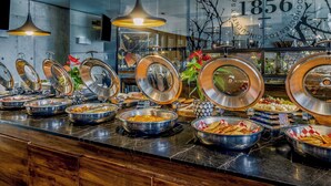 Un espace buffet proposant différents stands de nourriture, avec notamment des saladiers remplis de fruits, de légumes et d’autres plats.